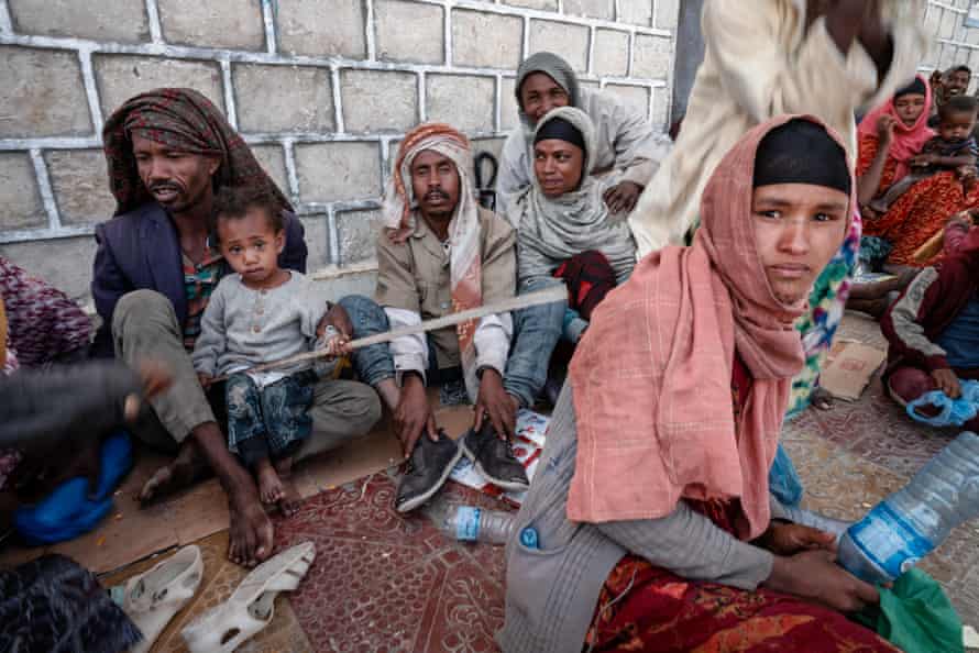 Families shelter in the shade on a street