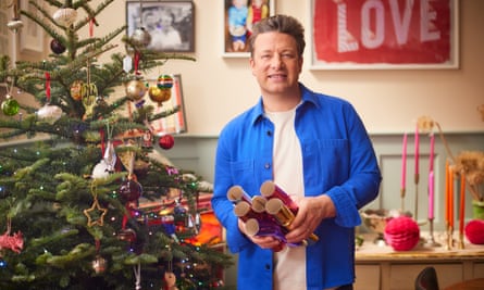 Jamie Oliver standing beside a Christmas tree