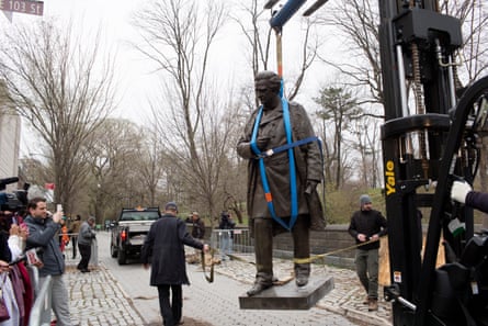 a monument being taken down in a park as people look on