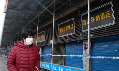 A woman walks by a closed seafood market in Wuhan on 12 January.