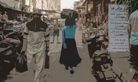 An African woman carries a suitcase on her head though a crowded street with signs in Arabic outside a shop