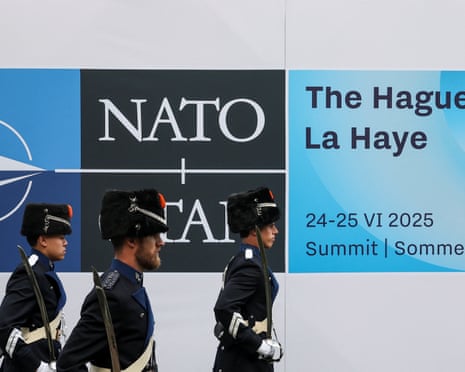Members of the military wearing ceremonial uniforms walk at the venue next to a Nato logo, on the day of a Nato leaders summit in The Hague, Netherlands.
