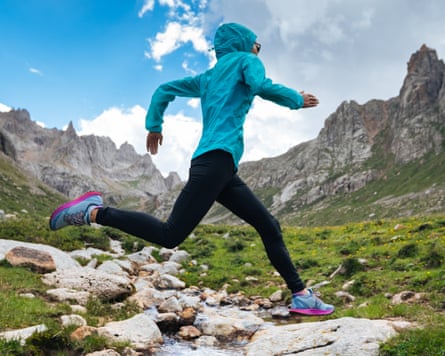 Trail runner jumping complete a mini river.