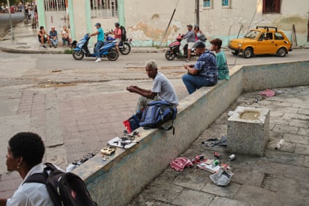 People sit on a curb on a city corner and sell items.