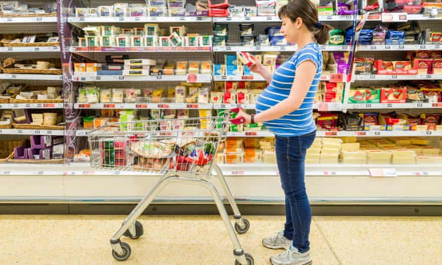 Pregnant woman checking label on cheese at Sainsbury’s supermarket, UKMY96DM Pregnant woman checking label on cheese at Sainsbury’s supermarket, UK Model release