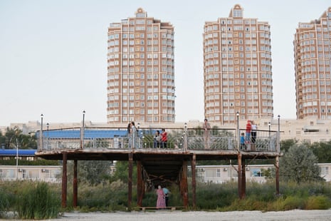 People stand on and beneath a pier that was originally built in water in the Caspian Sea.