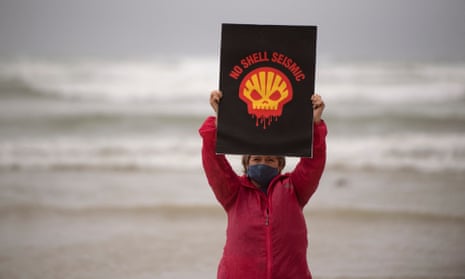 protester on beach holding a sign saying no to shell