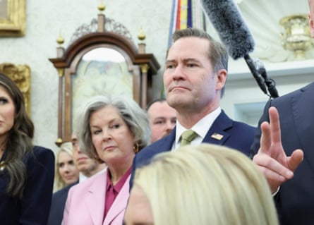 woman in pink suit stands next to man in navy suit