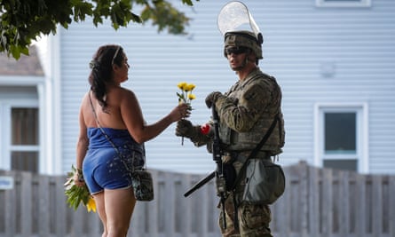 Kenosha marches on as protesters describe 'kidnap' by federal agents | Wisconsin 5 A woman hands flowers to a member of the Wisconsin national guard standing by as people gather for a vigil on Friday, following the police shooting of Jacob Blake.