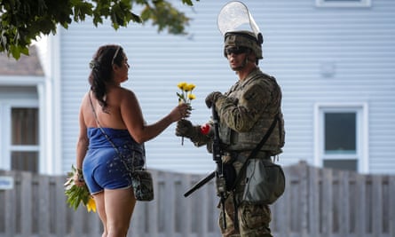 A woman hands flowers to a member of the Wisconsin national guard standing by as people gather for a vigil on Friday, following the police shooting of Jacob Blake.