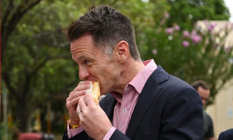 Chris Minns enjoys a democracy sausage as he visits a polling booth at Narwee Public School in Narwee.