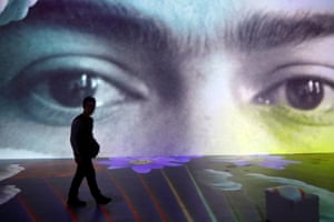 A person walks past a large screen featuring a closeup of Kahlo’s face