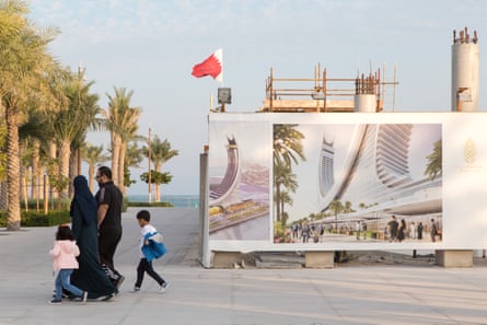 People walk past signs for a luxury hotel under construction in the marina district