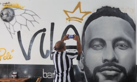 A fan takes a picture of a mural depicting Neymar at Santos.