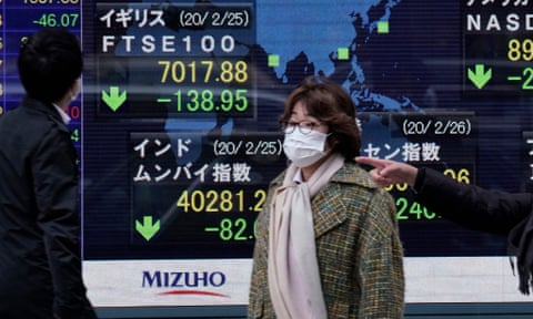 Pedestrians walk past a display showing information of global stock markets in Tokyo.