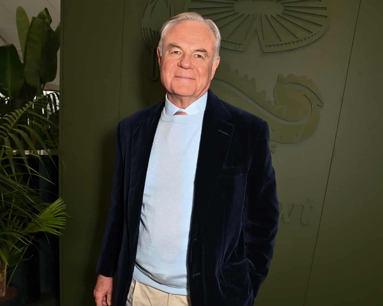 Koos Bekker: he is in his 70s with white hair, and wears a dark blue jacket, pale blue shirt, light sand trousers.