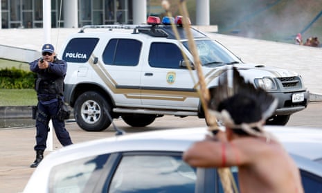 A member of Brazil’s riot police trains his gun at Brazilian Indians