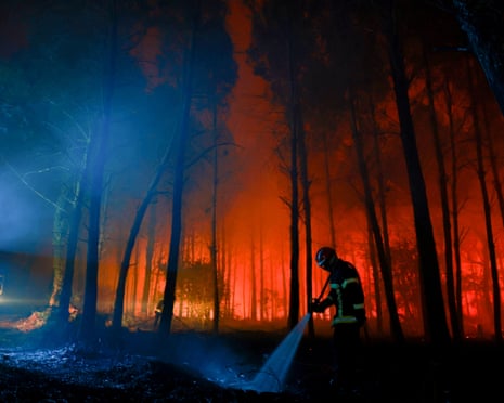 A firefighter hoses down the charred ground as flames continue to burn in the Landes forest in Luglon, southwestern France.