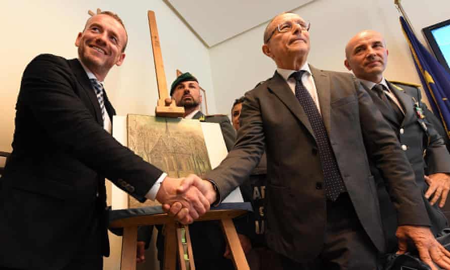 Axel Rütger, director of the Van Gogh Museum in Amsterdam (left), and Naples prosecutor Giovanni Colangelo shake hands in front of the recovered  Van Gogh painting Congregation Leaving the Reformed Church in Nuenen.