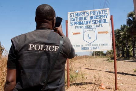 A member of the security forces takes photos of St. Mary’s Private Catholic School signage in Papiri, Niger State, Nigeria.