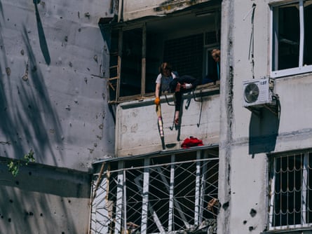 People trying to clear debris and reach belongings through a broken window