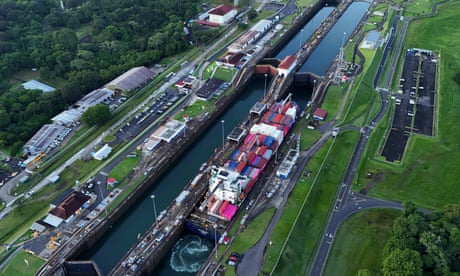 A cargo ship carrying dozens of containers passes through a lock