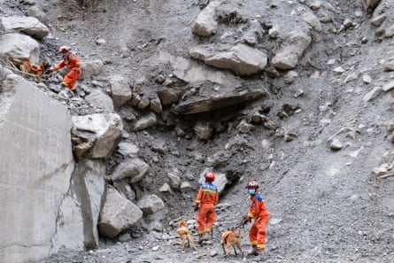 Firefighters and sniffer dogs search for missing people on a road near Gyirong Port