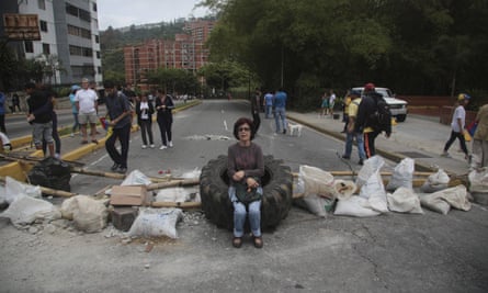 A woman rests on a tyre at a roadblock set up by residents outside her home in El Hatillo, near Caracas, on Tuesday.