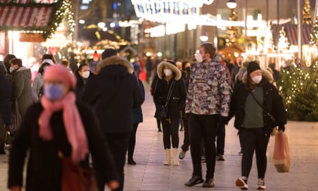 People, many wearing protective face masks, walk through a Christmas market in Berlin, Germany, as the city reports its first Omicron case.