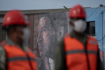 Workers in hi-vis vests, hard hats and dust masks in front of portrait of Chávez