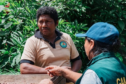 Two people stand by a wooden trough.