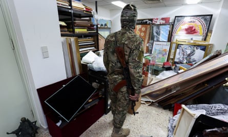 A rebel fighter looks at Bashar al-Assad’s personal souvenirs and items in a room at the presidential palace, 10 December 2024.