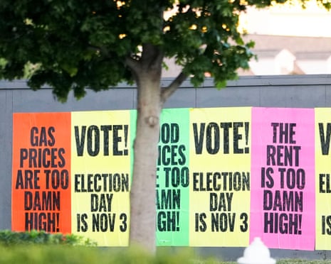 Colorful signs posted on a wall outside with messages such as 'The rent is too damn high!' and 'Vote! election day is Nov 3'