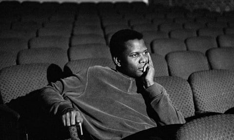 Sidney Poitier sitting pensively in empty cinema stalls, on the set of For Love of Ivy, New York, 1968