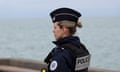 Grey sea and side view of officer with Police Nationale label on back of black uniform