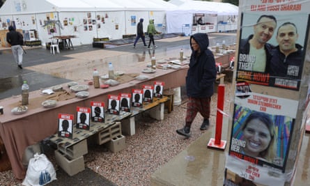 People walk near a long table surrounded by empty chairs symbolizing the hostages held by Hamas in Gaza
