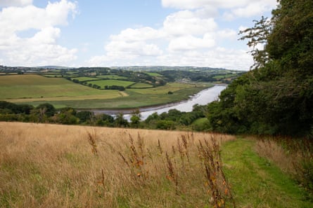 A glimpse of a curving river seen between two gently rolling hills