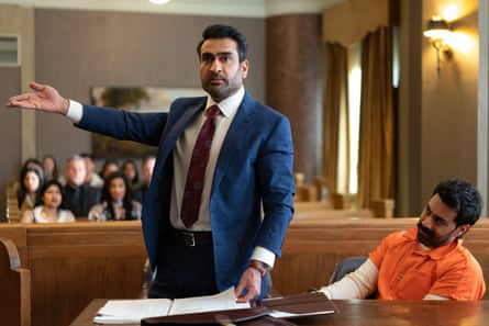 A lawyer in court standing up with a man in an orange jumpsuit sitting next to him