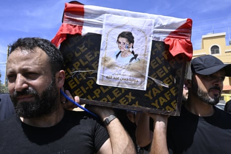 Two men with pained faces carry a coffin with the photo of a young girl taped to the front.