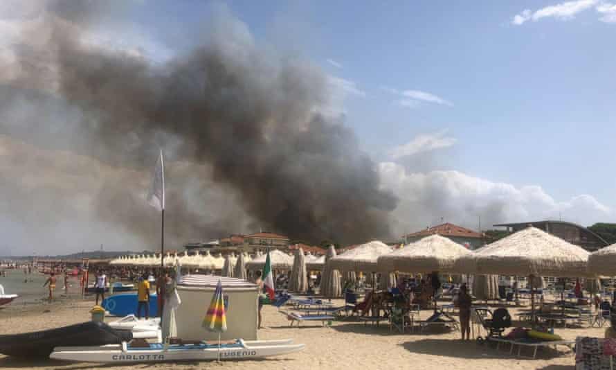 Smoke billows from the Dannunziana nature reserve as people watch from the beach at Pescara on Sunday