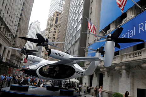 an air taxi on display on a street with tall buildings