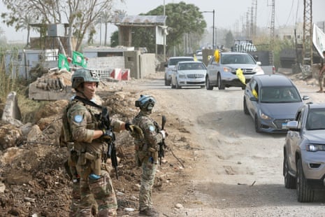 Unifil peacekeepers watch as cars drive past.