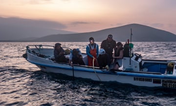Dr Alex Hearn and his colleagues in a boat in fading light tagging a shark in the Galápagos marine reserve.