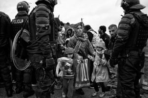 A mother guides her children through a line of Slovenian police at the border crossing with Croatia, 2015