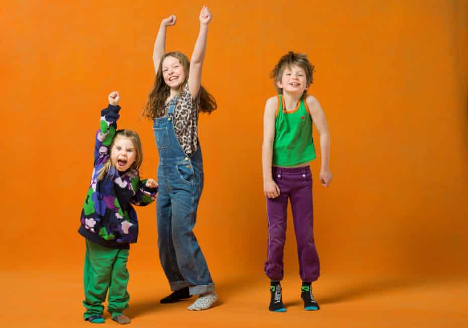 Three young children in rented clothes, two with their arms up in celebration