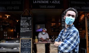A bartender waits for customers behind a makeshift counter lining the sidewalk in Paris