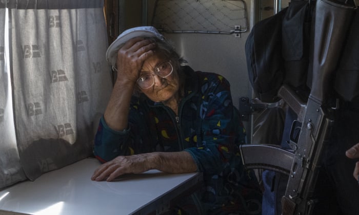 An elderly woman evacuated from the war-hit area sits inside an evacuation train waiting for departure while a soldier passes by her in Pokrovsk, eastern Ukraine.