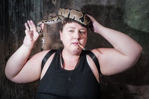 A woman, smoking, with a snake wrapped around the crown of her head