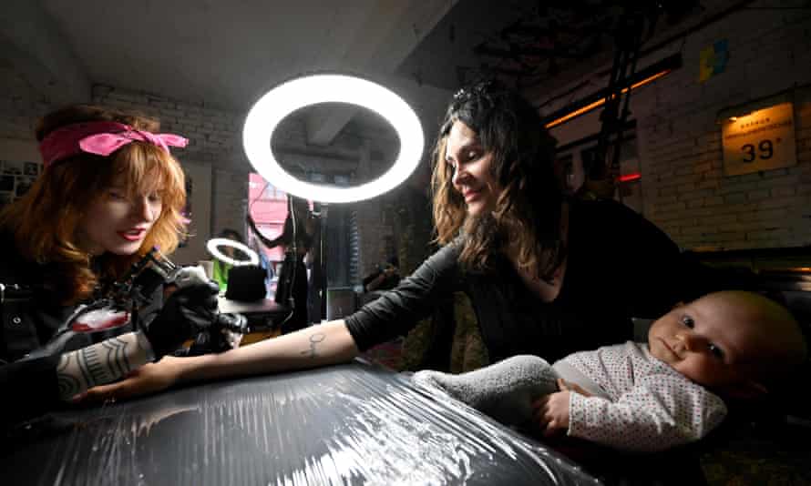 A Ukrainian woman holds her baby while getting a tattoo during the Art Weapon festival.