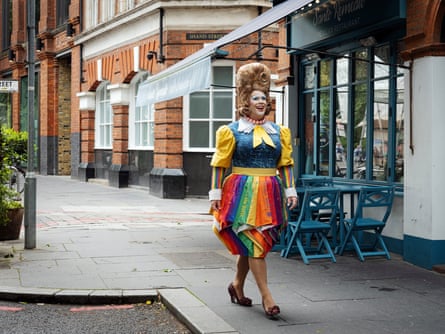 Mama G – in a theatrical, colourful outfit and tall brown wig – walking down the street